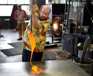 artisan soufflant le verre en atelier lumineux